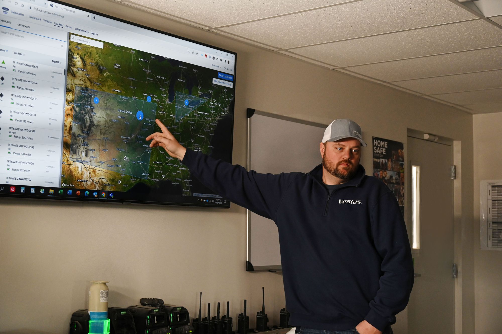 A photo of Kevin Schieber pointing to a screen showing a Ford Pro™ E-Telematics Live Map.