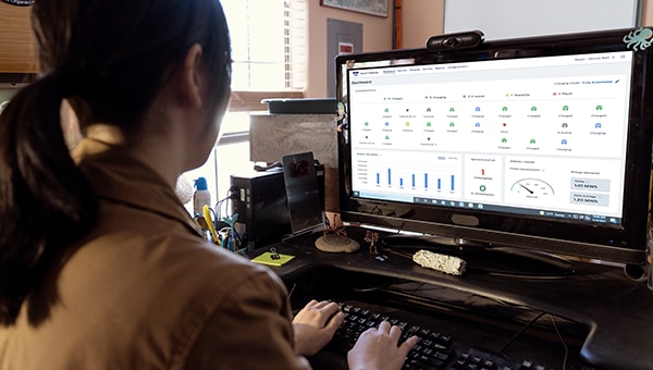 Vue de l’arrière d’une femme qui travaille sur un ordinateur affichant le logiciel de recharge Ford Pro.