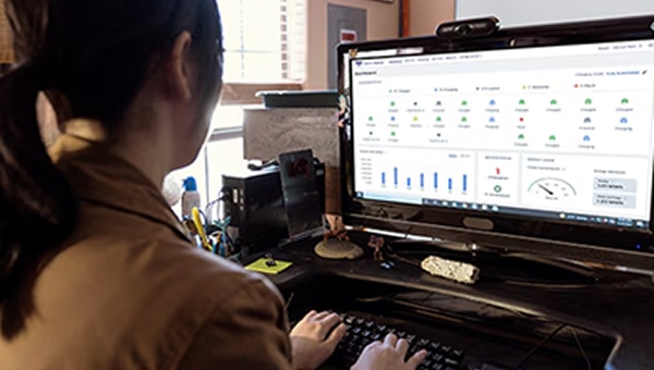 View of person from behind as they work on a tablet displaying Ford Pro E-Telematics Software.