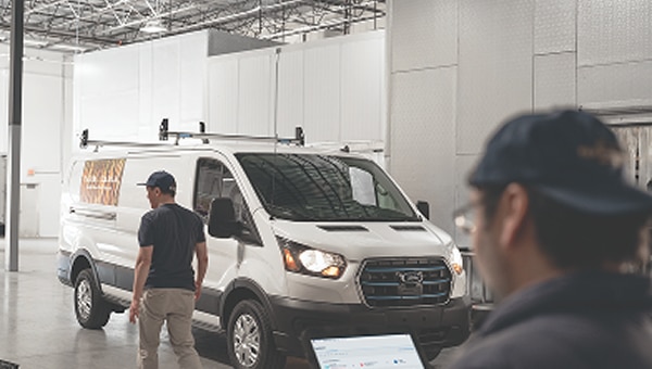 A person walking past a white Ford van.
