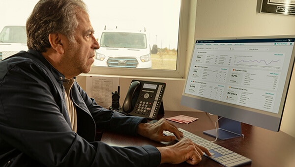 Un directeur assis à un bureau devant un ordinateur portable examine un rapport en ligne.