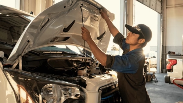 Ford technician opening the hood of a vehicle to perform maintenance.
