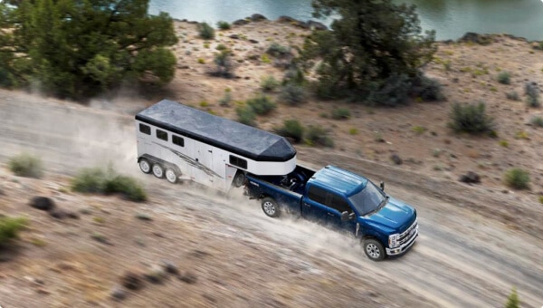 2024 Ford Super Duty® F-350® XLT in Antimatter Blue pulling a trailer on a dirt road
