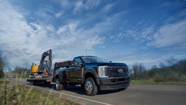 2024 Ford Super Duty® F-450® XL in Agate Black hitched to a trailer carrying a backhoe