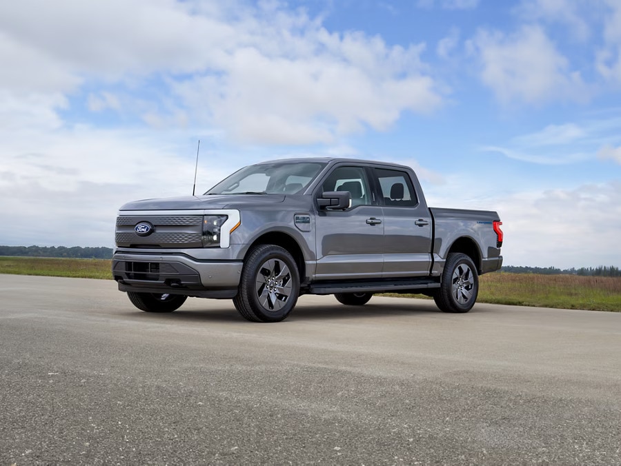 A dark grey 2024 Ford F-150 Lightning FLASH pickup truck parked on a rural road
