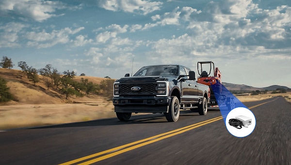 Image of a Ford F-250 XL towing construction equipment on a highway.