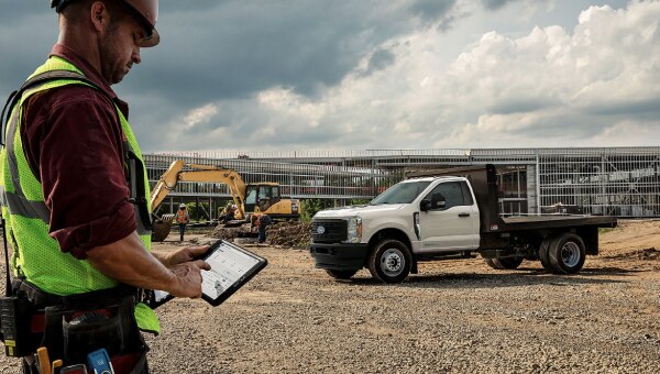 Construction worker using a tablet to check on vehicle health data.