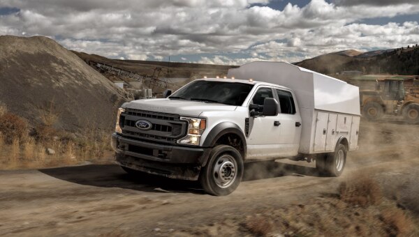 White service truck driving uphill on a construction site.