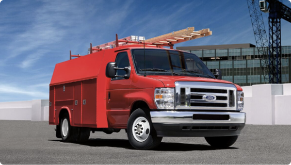 Camion utilitaire Ford rouge garé sur un chantier en activité, prêt à effectuer des travaux.