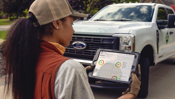 A person using a tablet in front of a truck.