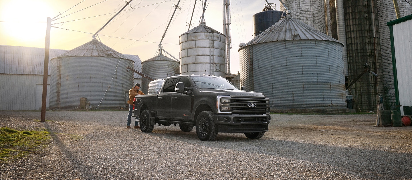 Un Ford Super Duty 2027 équipé de l’ensemble Carhartt garé sur un chantier à côté de grands silos à céréales.