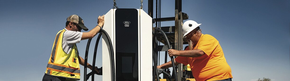 Técnicos instalando estación de carga eléctrica Ford Pro para vehículos comerciales.