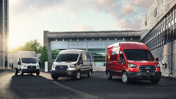 Van Ford E-Transit 100% eléctrica circulando pro la ciudad al anochecer.