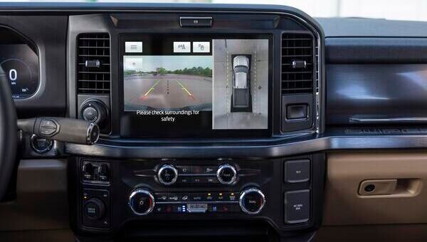 Interior de una Ford Super Duty F-250 mostrando su pantalla central con un sistema de cámaras de múltiples vistas, incluyendo una cámara trasera con guías y una vista aérea de 360 grados del vehículo
