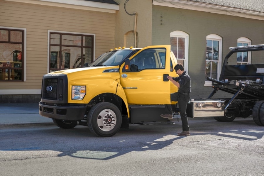 Trabajador abriendo la puerta de un camión Ford amarillo, se logra a notar que el camión viene diseñado como grúa.