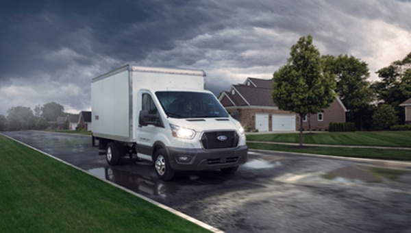 Ford Transit Chasis con caja de carga blanca en calle mojada.