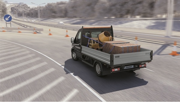 Ford Transit Chasis con plataforma transportando materiales de construcción en carretera.