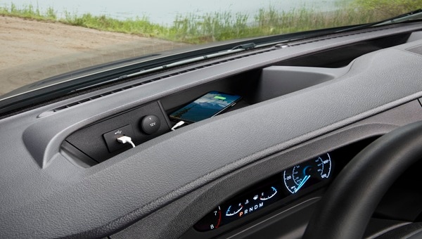 Compartimento de almacenamiento en el tablero de Ford Transit Chasis, con un teléfono cargando y puertos USB.