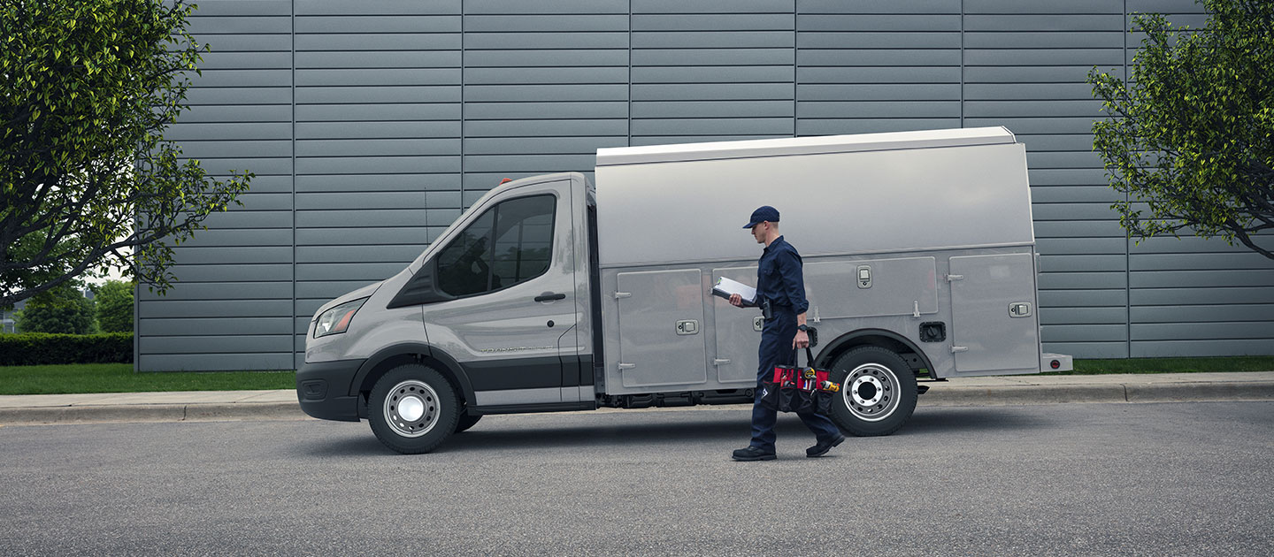 Ford Transit Chasis versátil adaptada como utilitario de servicio, estacionada frente a edificio moderno gris.