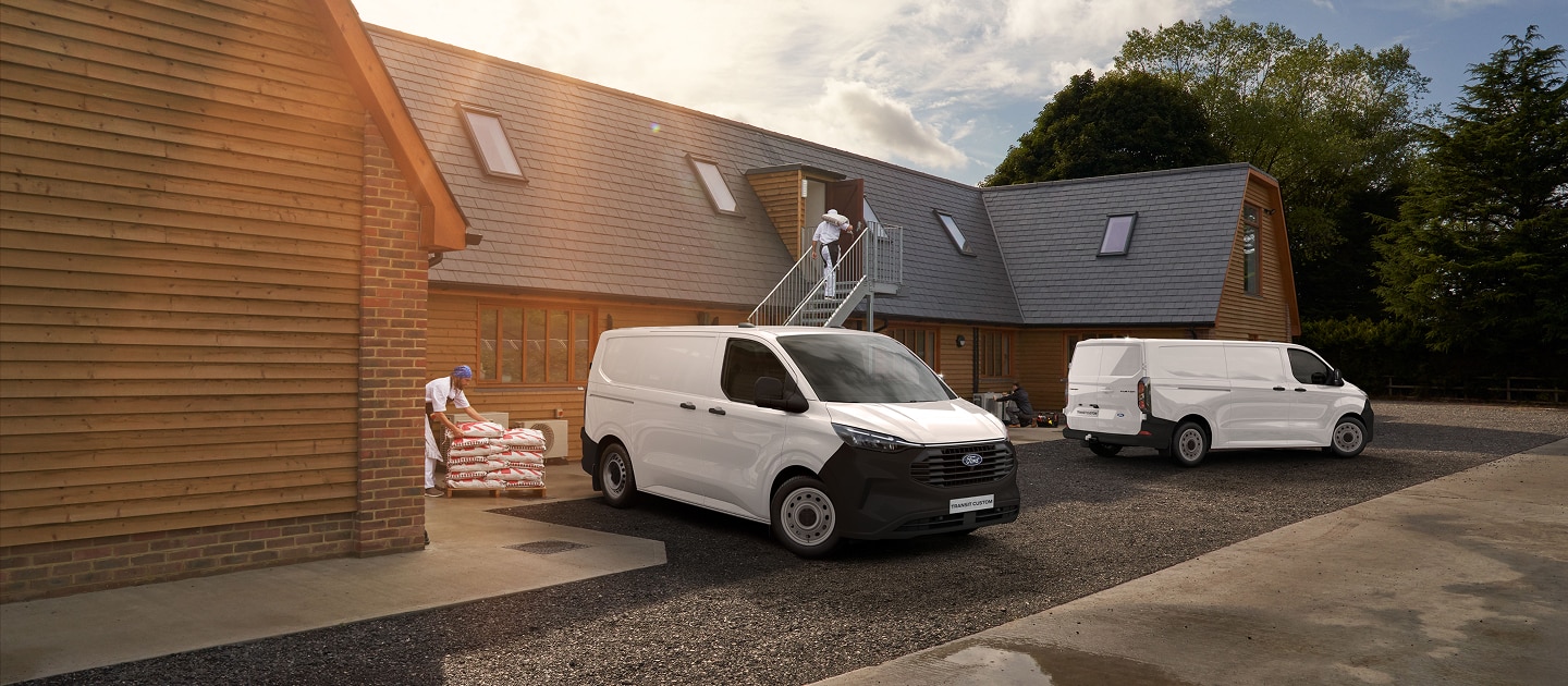 Dos vans Ford Transit Custom blancas en un entorno de trabajo, con operarios cargando materiales.