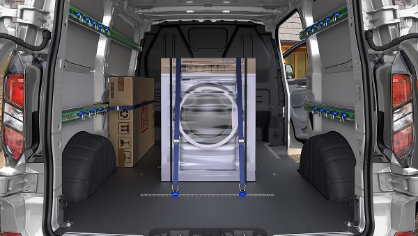 Espacio de carga de Ford Transit Custom 2026 con lavadora y caja aseguradas, mostrando estanterías modulares.