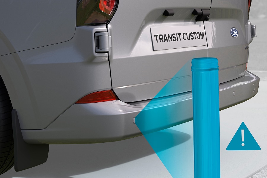 Parte trasera de una Ford Transit Custom gris, con una ilustración de un sensor de estacionamiento detectando un poste.
