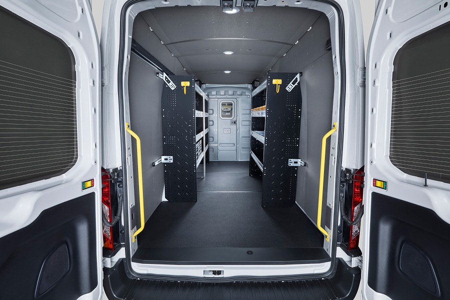 Interior de van con estanterías y puertas traseras abiertas.