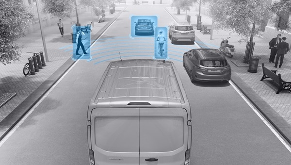 Ford Transit Van en calle urbana con sensores detectando peatones, ciclista y vehículo.