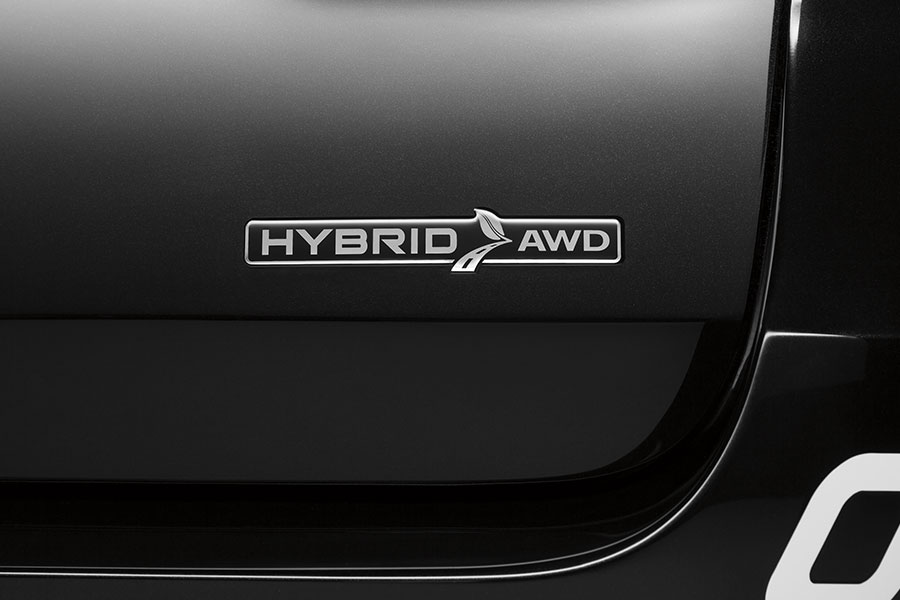 Primer plano del emblema metálico "HYBRID AWD", que destaca la combinación de motorización híbrida y tracción integral del vehículo sobre una carrocería oscura.