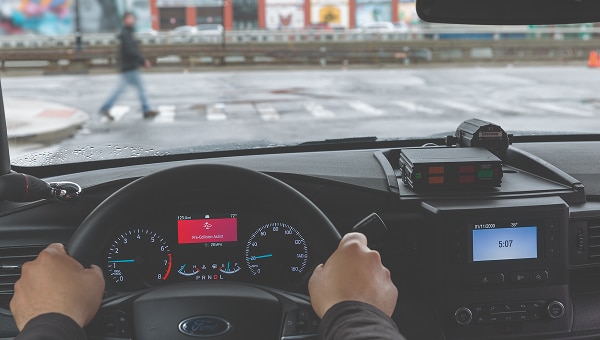 Interior de una Ford Explorer Police Interceptor desde el conductor, mostrando el volante, el tablero con alerta de "Pre-Collision Assist; y un dispositivo policial en la consola.