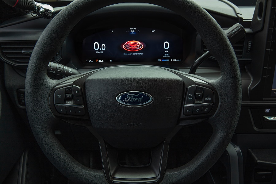 Primer plano del volante y el panel de instrumentos digital de un Ford Police Interceptor Utility, mostrando el modo 'Pursuit' y 'Responsive Performance' en la pantalla.