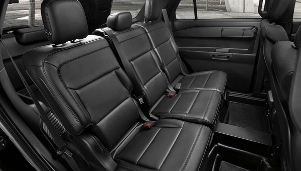 Vista interior de la segunda fila de asientos de Ford Police Interceptor 2025, mostrando los asientos de vinil negros y las ventanas con película de privacidad.