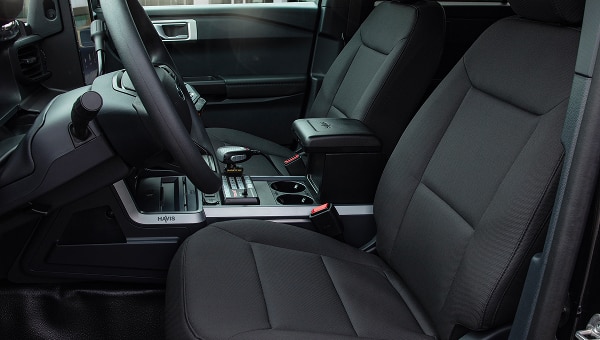 Interior de Ford Police Interceptor Utility, mostrando los asientos delanteros negros de tela, el volante y una consola central personalizada
