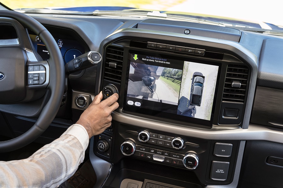Interior de Ford Lobo 2026, mostrando una mano girando el control de la Asistencia para Estacionado de Remolque Pro, mientras la pantalla central muestra vistas de la cámara para guiar el remolque. Capacidad de remolque.
