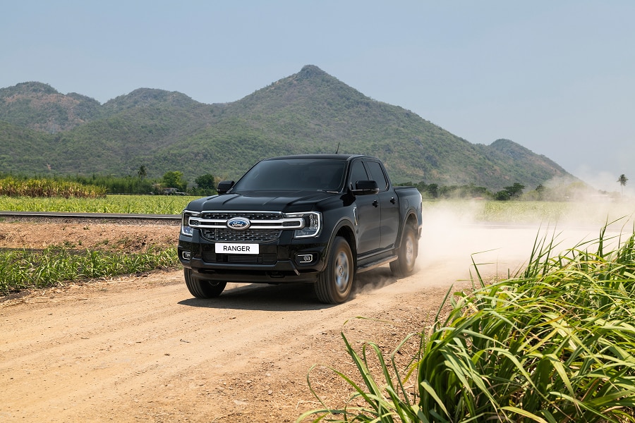 Ford Ranger negra en camino de tierra levantando polvo, con montañas al fondo.