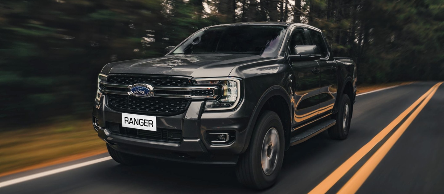 Ford Ranger 2026 oscura en carretera boscosa.