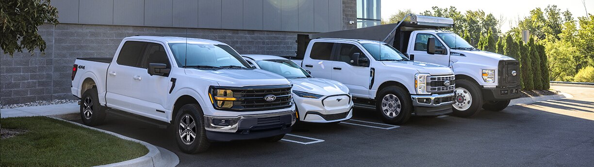 Flota de pickups Ford y mustang Mach-E frente a edificio industrial.
