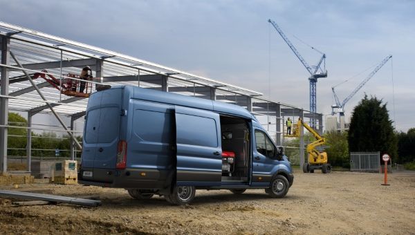 Ford Transit bestelwagen met voertuig-gemonteerde kraan op bouwplaats.