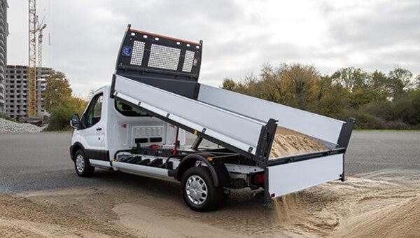 Ford Transit kiepwagen lost zand op bouwplaats