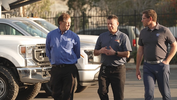 Ford Pro team members discussing work beside commercial pickup trucks.