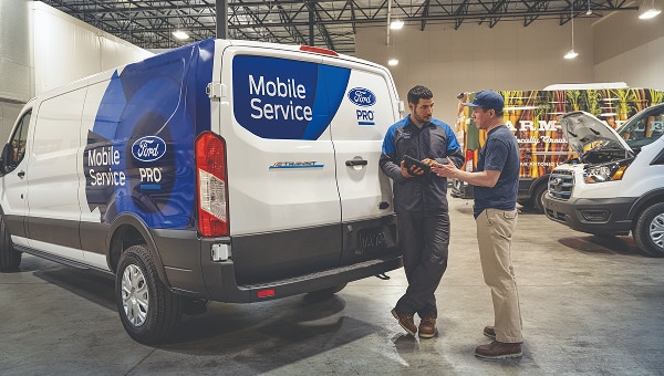 Ford Mobile Service van with technicians performing vehicle maintenance in a service facility.