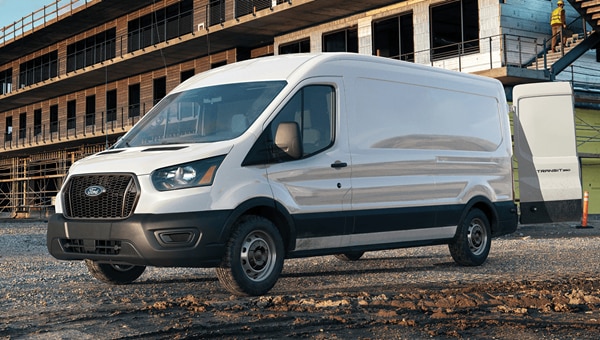A white Ford Transit Cargo Van being unloaded in front of a building that is under construction.