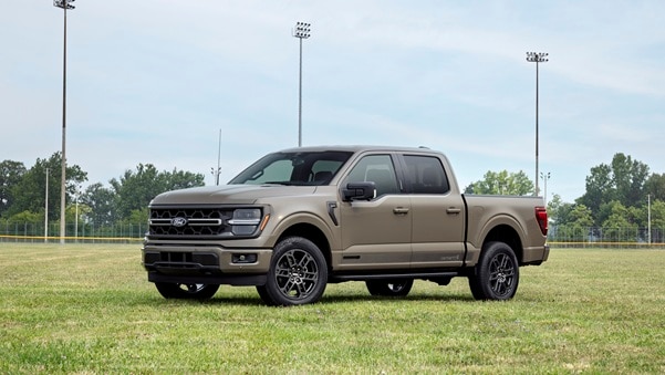 Ford F-150 x Carhartt special edition pickup truck – beige exterior, all-terrain wheels, parked on a sports field, front three-quarter view.