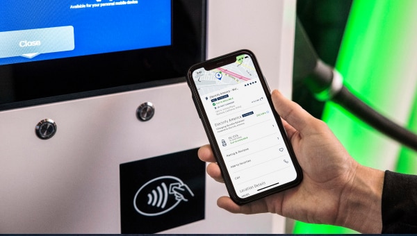 Person holding a phone next to an EV charging station.