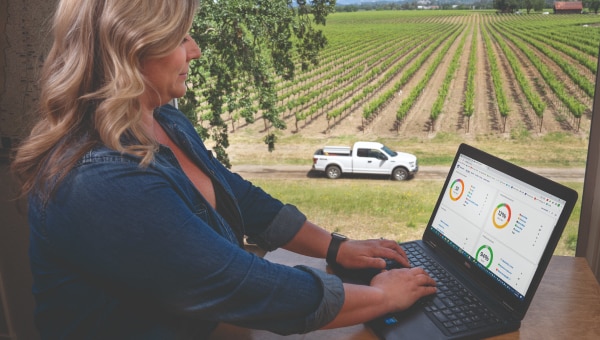 Woman using Ford Pro™ Telematics with a Ford truck parked in a field in the background