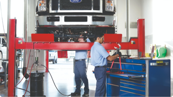 Two service technicians working on a truck in a service center.