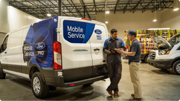Two service technicians communicating with each other beside a Mobile Service van.