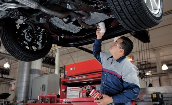 Mechanic performing an oil change with Motorcraft parts.