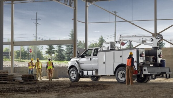 Workers near 2027 Ford F-750 SuperCab in Oxford White with mechanic truck upfit parked at construction site