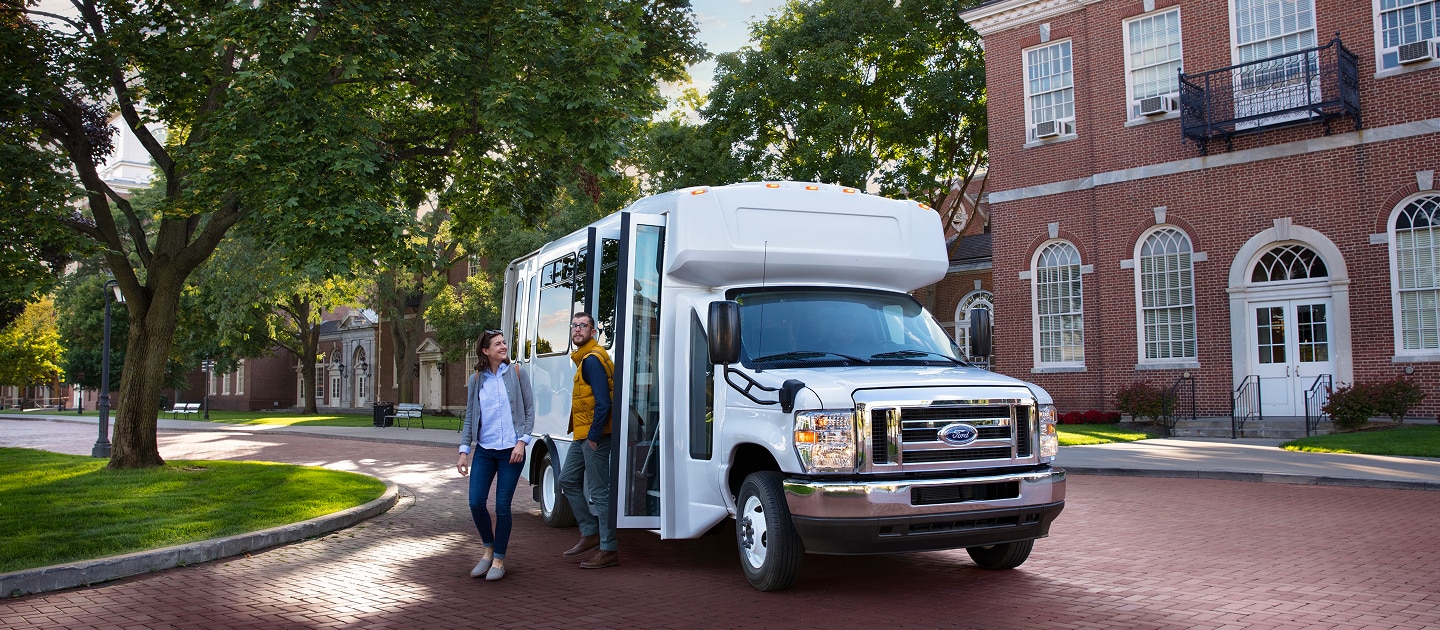 Image of a shuttle bus parked in front of a building with people exiting the bus